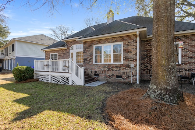 rear view of house with crawl space, brick siding, a yard, and a deck