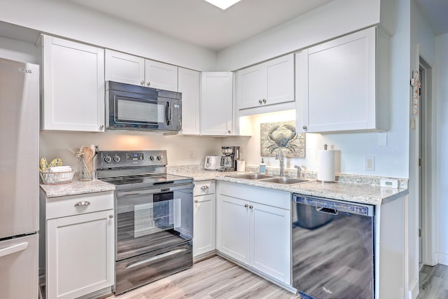 kitchen with black appliances, white cabinets, sink, and light hardwood / wood-style flooring