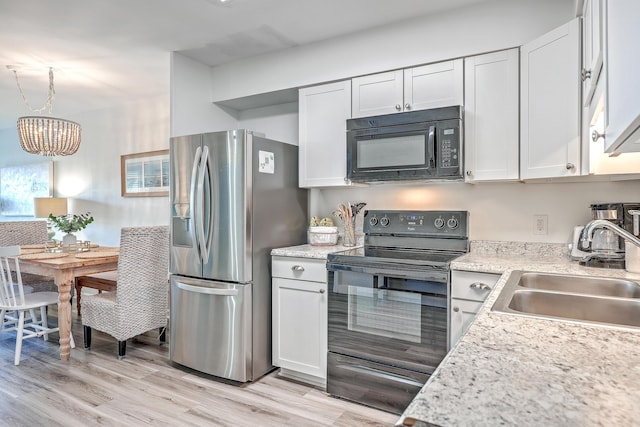 kitchen with pendant lighting, black appliances, white cabinetry, sink, and a notable chandelier