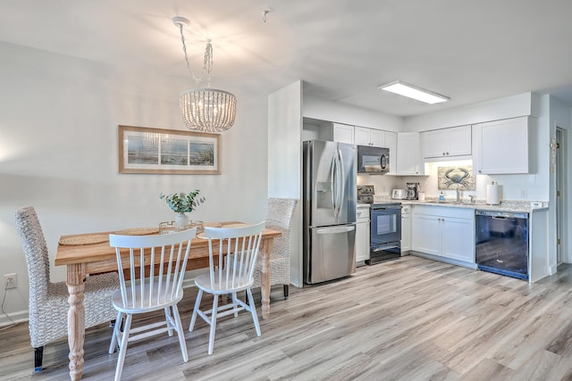 kitchen featuring light stone countertops, black appliances, white cabinetry, a chandelier, and light hardwood / wood-style flooring