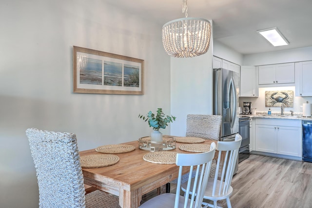 dining area with light wood-type flooring and a notable chandelier