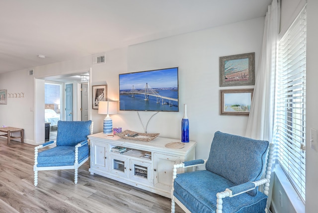 living area with a wealth of natural light and light hardwood / wood-style flooring