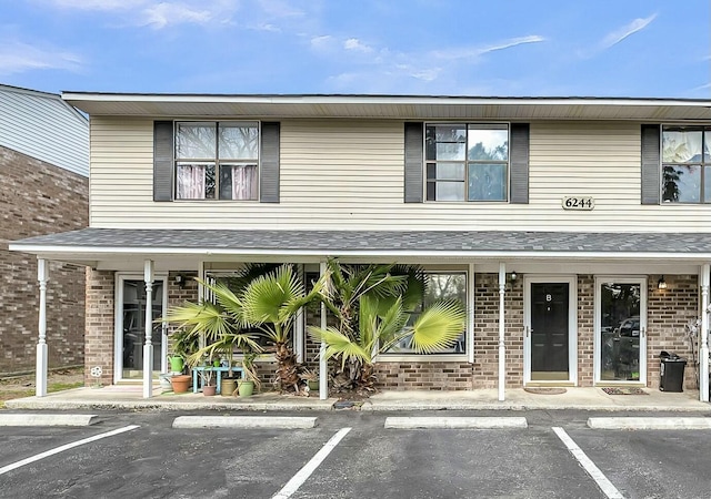 view of front of house with uncovered parking and brick siding