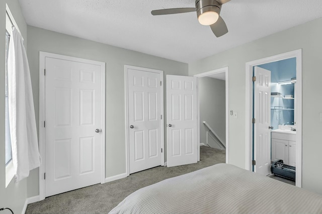 carpeted bedroom with ensuite bathroom, ceiling fan, a sink, and baseboards