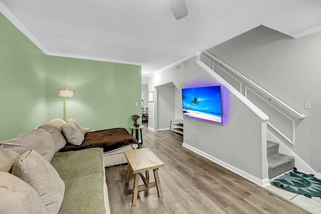 living room with stairs, ornamental molding, a textured ceiling, and wood finished floors