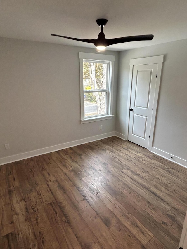 spare room featuring ceiling fan, baseboards, and dark wood-style floors