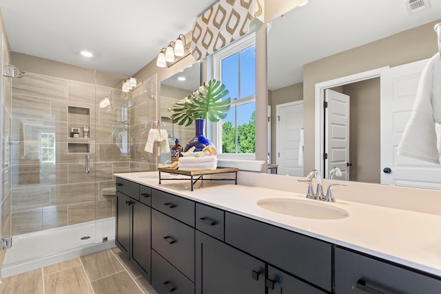 bathroom featuring a shower with door and vanity