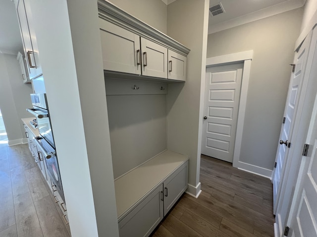 mudroom with dark wood-type flooring and crown molding