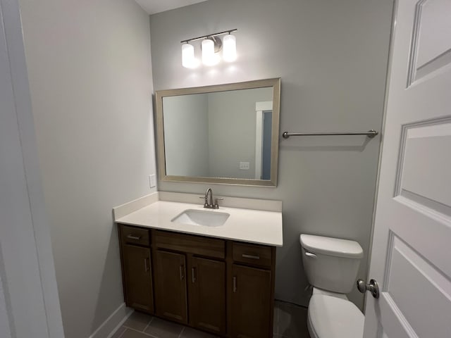 bathroom with toilet, vanity, and tile patterned flooring