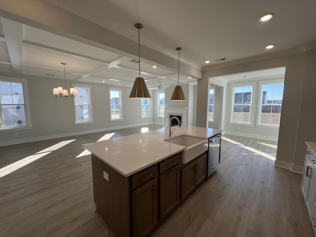 kitchen featuring dishwasher, sink, an inviting chandelier, hanging light fixtures, and dark hardwood / wood-style flooring