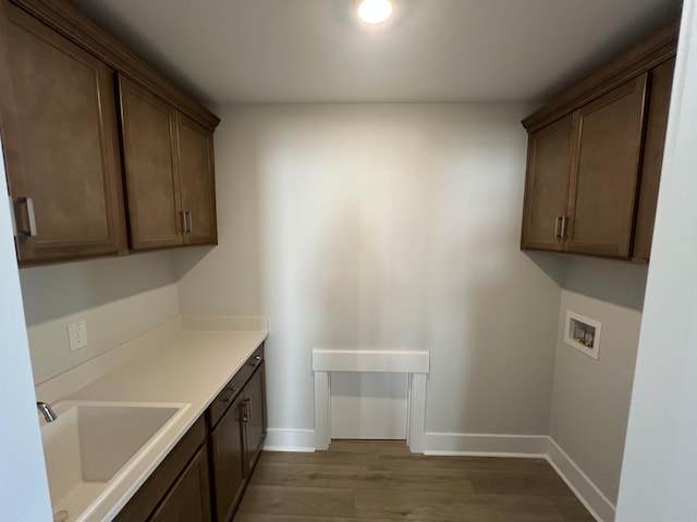 laundry area with cabinets, sink, hookup for a washing machine, and light wood-type flooring