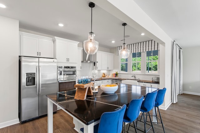 kitchen featuring white cabinetry, stainless steel appliances, tasteful backsplash, dark hardwood / wood-style flooring, and a kitchen island