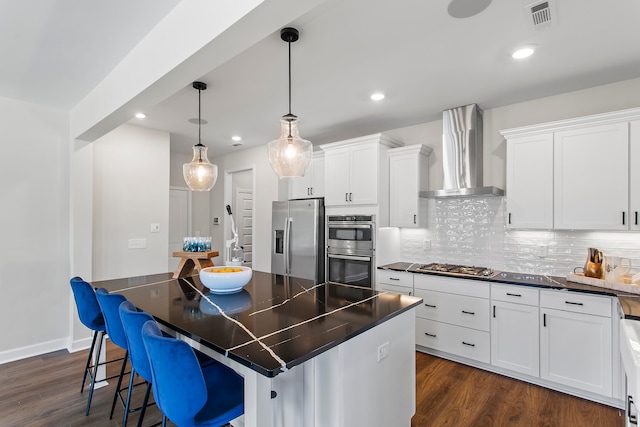 kitchen featuring stainless steel appliances, a center island, white cabinets, and wall chimney range hood