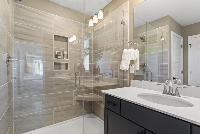 bathroom featuring a shower with shower door and vanity