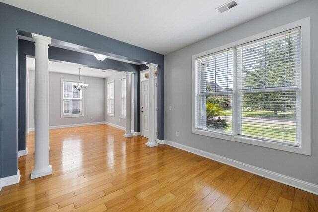 1070 Moss Grove Dr, Moncks Corner, SC 29461 - unfurnished room featuring decorative columns, a chandelier, and light wood-style floors
