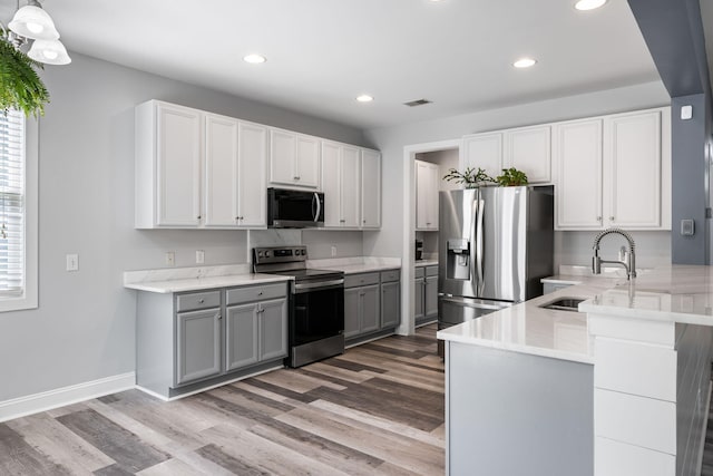 1070 Moss Grove Dr, Moncks Corner, SC 29461 - kitchen with appliances with stainless steel finishes, light wood-style floors, gray cabinetry, recessed lighting, and a peninsula