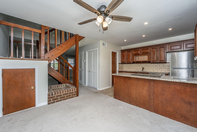 kitchen featuring tasteful backsplash, freestanding refrigerator, light colored carpet, and light stone counters