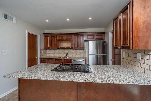 kitchen with light stone counters, stainless steel appliances, a peninsula, a sink, and visible vents