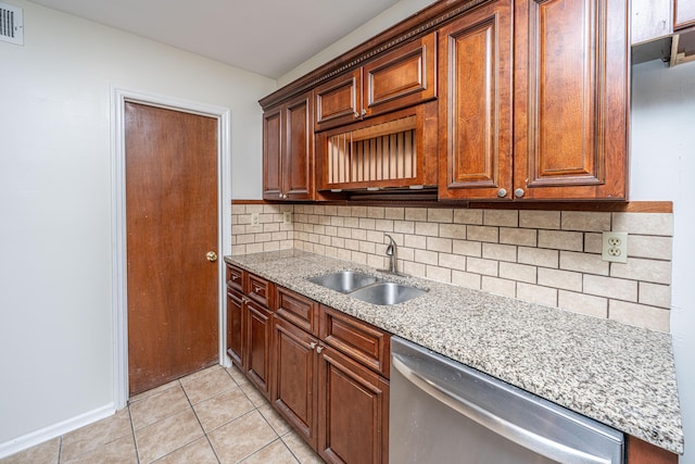 kitchen with light stone counters, backsplash, light tile patterned flooring, a sink, and dishwasher