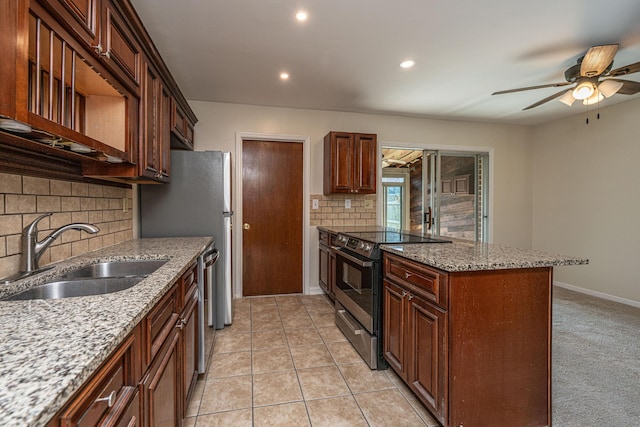 kitchen with a ceiling fan, appliances with stainless steel finishes, light stone countertops, a sink, and light tile patterned flooring