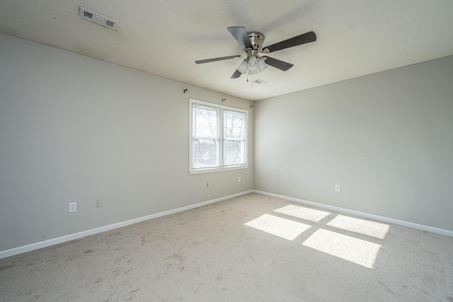 empty room featuring light carpet, baseboards, visible vents, and a textured ceiling