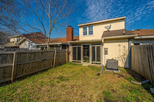 back of property with a sunroom, a fenced backyard, a chimney, and a yard