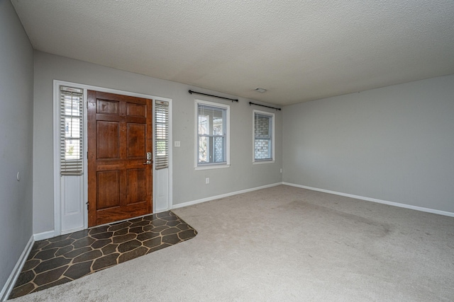 carpeted entrance foyer with a textured ceiling and baseboards