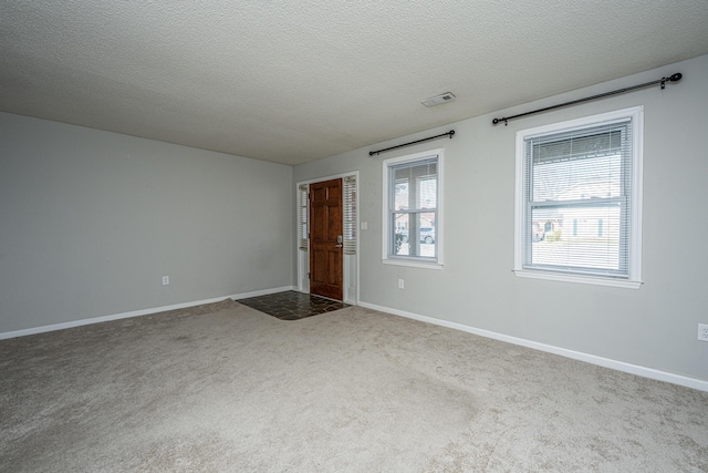 empty room with a textured ceiling, carpet floors, and baseboards