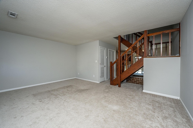 spare room featuring carpet floors, visible vents, stairway, a textured ceiling, and baseboards