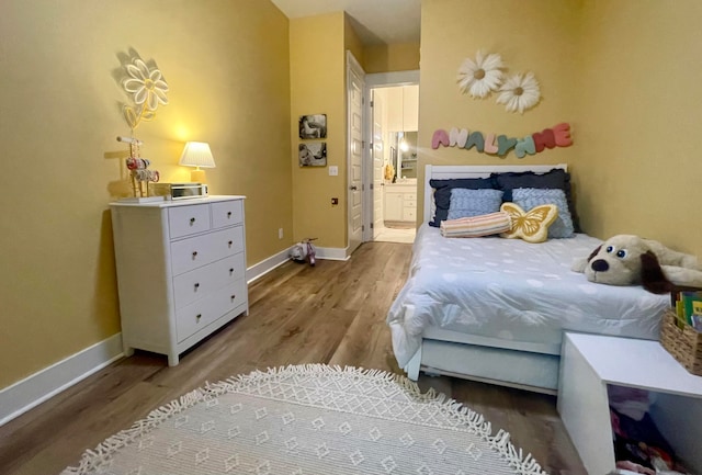 bedroom featuring ensuite bath and light hardwood / wood-style floors