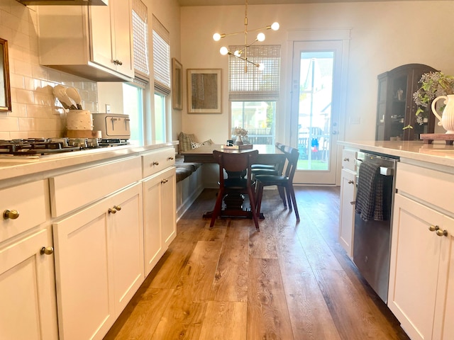 kitchen featuring light wood-type flooring, white cabinetry, an inviting chandelier, and pendant lighting