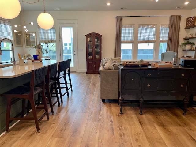 living room with light hardwood / wood-style flooring, sink, and a healthy amount of sunlight