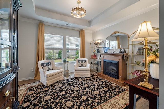 143 Daniels Creek Cir, Goose Creek, SC 29445 - living area featuring a fireplace with raised hearth, wood finished floors, a chandelier, a tray ceiling, and baseboards