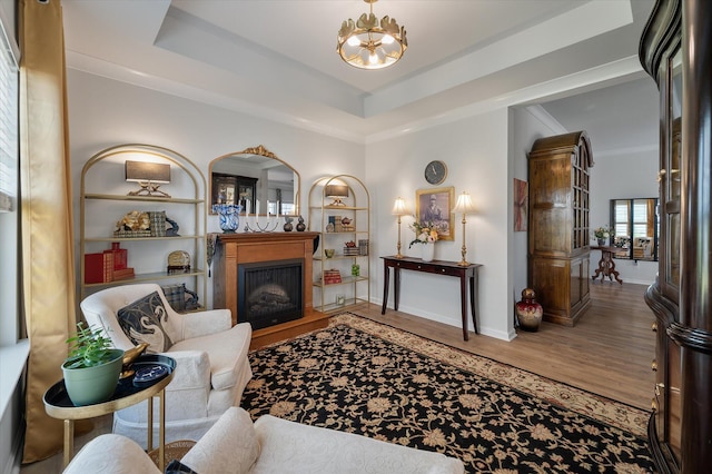 143 Daniels Creek Cir, Goose Creek, SC 29445 - living area featuring a fireplace with raised hearth, wood finished floors, a chandelier, baseboards, and a tray ceiling