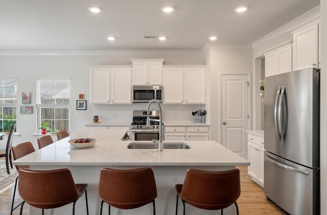 143 Daniels Creek Cir, Goose Creek, SC 29445 - kitchen with stainless steel appliances, crown molding, a sink, white cabinetry, and a kitchen bar