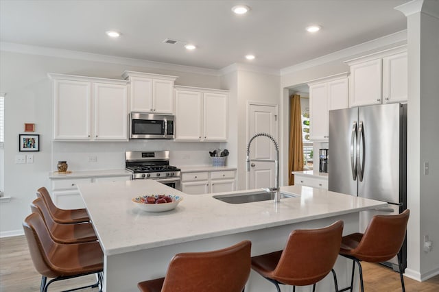 143 Daniels Creek Cir, Goose Creek, SC 29445 - kitchen with stainless steel appliances, light wood-style flooring, white cabinetry, a kitchen bar, and a center island with sink