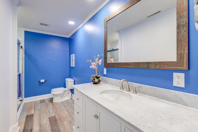 bathroom with walk in shower, ornamental molding, vanity, wood-type flooring, and toilet