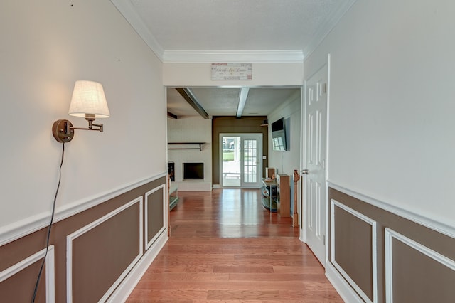 corridor featuring light hardwood / wood-style floors, ornamental molding, and beam ceiling