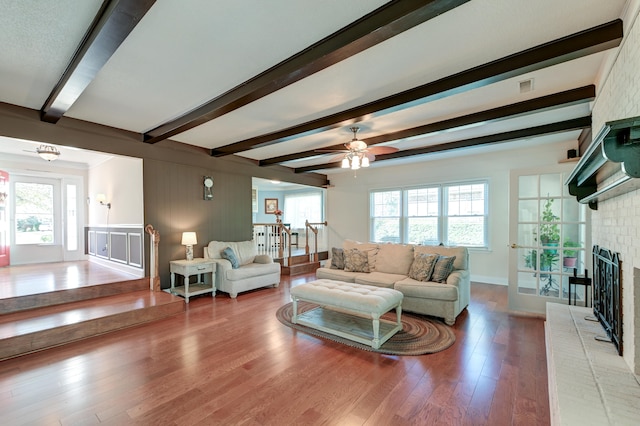 living room featuring beamed ceiling, a healthy amount of sunlight, and wood-type flooring