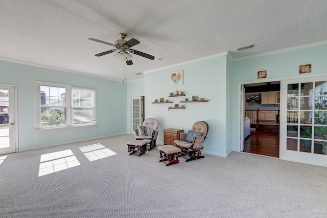 sitting room with carpet, a textured ceiling, ceiling fan, and ornamental molding