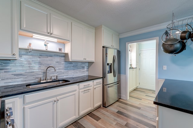 kitchen featuring backsplash, white cabinets, sink, stainless steel refrigerator with ice dispenser, and light hardwood / wood-style flooring