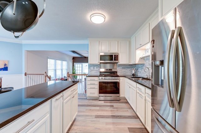 kitchen with sink, white cabinetry, stainless steel appliances, and ornamental molding