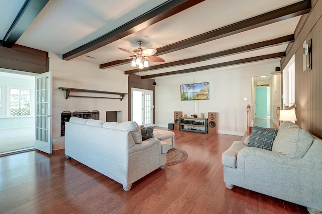 living room with beam ceiling, ceiling fan, plenty of natural light, and dark wood-type flooring