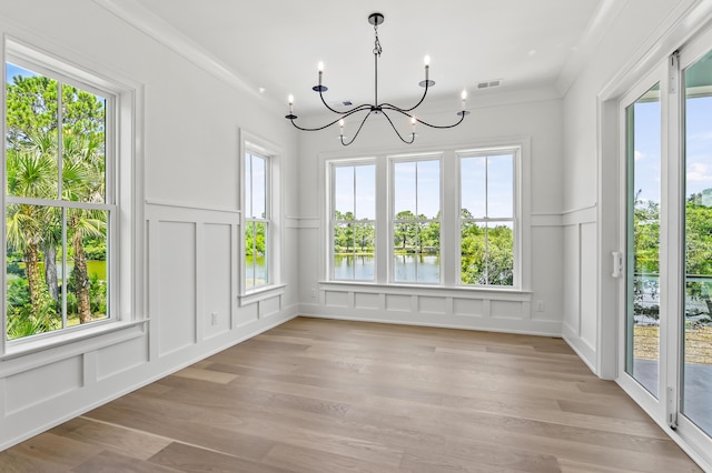 unfurnished dining area with a notable chandelier, ornamental molding, light hardwood / wood-style floors, and a water view