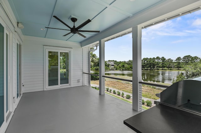 sunroom featuring ceiling fan and a water view