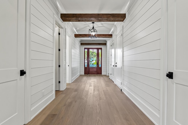 entryway with beamed ceiling, wooden walls, light hardwood / wood-style floors, and french doors