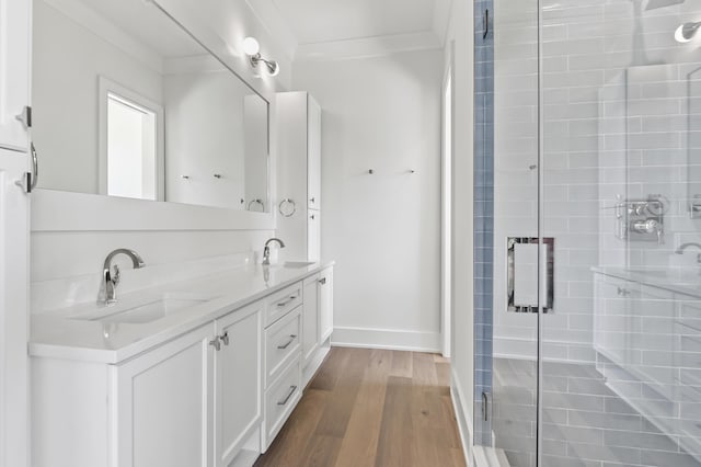 bathroom with hardwood / wood-style flooring, ornamental molding, a shower with shower door, and vanity