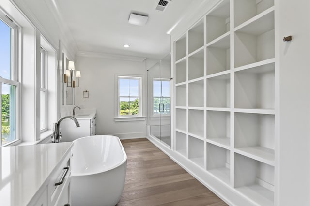 bathroom featuring hardwood / wood-style flooring, ornamental molding, plenty of natural light, and a bath