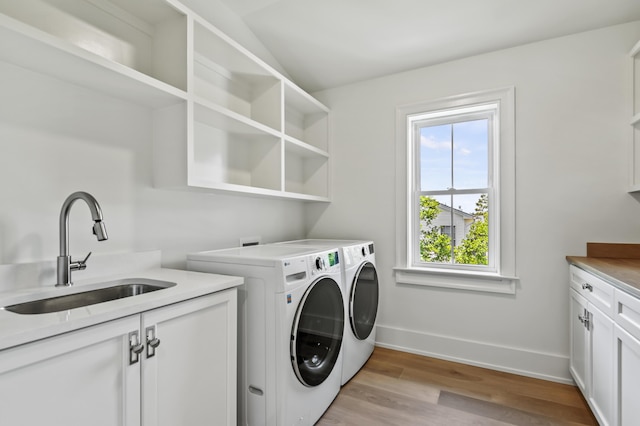 washroom featuring light wood-type flooring, cabinets, sink, and washing machine and clothes dryer