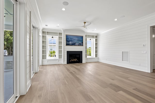 unfurnished living room with ornamental molding, a fireplace, and light wood-type flooring